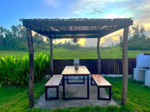 een tafel en banken onder een houten pergola bij Secret Villa - Unique Experience in General Luna