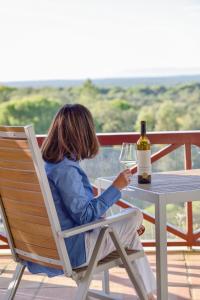 una mujer sentada en una mesa con una copa de vino en A Serenada Enoturismo, en Grândola