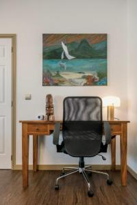 a desk with a chair in front of a painting at Grand Large - Premium suite in Papeete