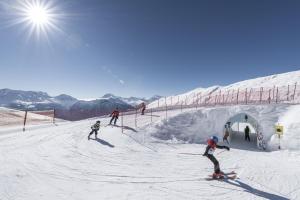 grupa osób jeżdżących na nartach po pokrytym śniegiem stoku w obiekcie Hotel Harmony Tigilou Belalp w mieście Belalp