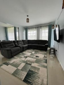 ein Wohnzimmer mit einem schwarzen Sofa und einem Teppich in der Unterkunft Zoe Homes 1br and 2br Apartment Greypoint 406 in Kericho