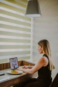 een vrouw die aan een bureau zit met behulp van een laptop bij Hotel Real Maestranza in Guadalajara