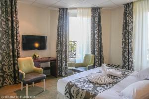 una camera d'albergo con un letto, due sedie e una TV di Hôtel Le Bristol Strasbourg Gare a Strasburgo