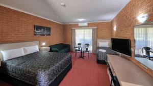 ein Hotelzimmer mit einem Bett, einem Sofa und einem TV in der Unterkunft Glider City Motel Benalla in Benalla