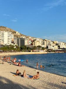 grupa ludzi na plaży z wodą i budynkami w obiekcie Taulant w Sarandzie