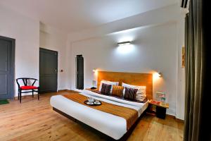 a hotel room with a large bed and a red chair at Divine Inn Couple Friendly Hotel near Sector 51 Metro Station in Noida