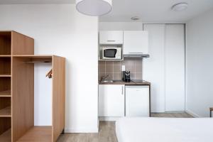 cocina con armarios blancos y microondas en Residhotel Le Central'Gare, en Grenoble