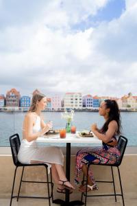 deux femmes assises à une table devant l'eau dans l'établissement Harbor Hotel & Casino Curacao, à Willemstad