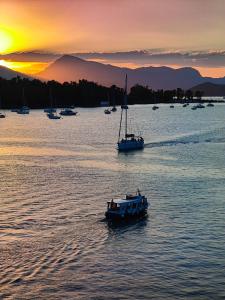 zwei Boote in einem großen Wasserkörper bei Sonnenuntergang in der Unterkunft The Manessi City Boutique Hotel in Poros