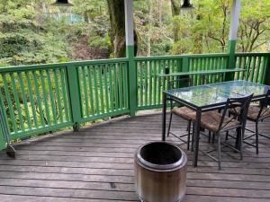 una mesa de cristal y sillas en una terraza de madera en Klingelbaer, en Hakone