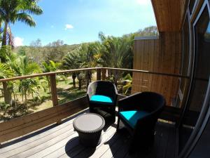 een balkon met 2 stoelen en een tafel en uitzicht bij Betikure Parc Lodge in Bourail