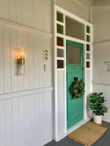 uma porta da frente com uma porta verde com uma planta em Gorgeous Arthouse Queenslander In Ipswich em Bundamba