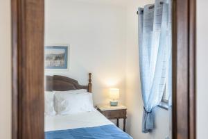 a bedroom with a bed with a blue blanket and a window at Cabo de Sagres -2 bedroom apartment in Sagres