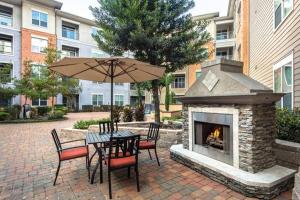 een patio met een tafel met een parasol en een open haard bij Home felt apartment- Med Center/NRG in Houston