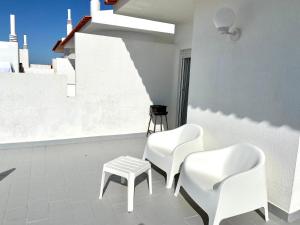 Dos sillas blancas y un taburete en una habitación en Ericeira Panoramic Sea View Apartments, en Ericeira