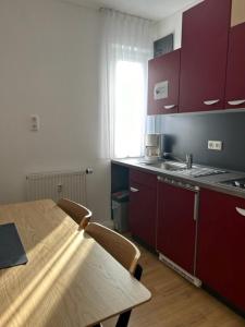 una cocina con armarios rojos y una mesa con sillas. en Aparthotel Gartenstadt, en Bamberg