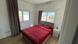 1 dormitorio con 1 cama roja y 2 ventanas en Tetris Apartment Spacious Comfortable, en Lefkosa Turk