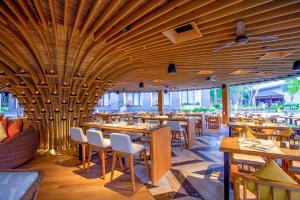 un restaurante con techos de madera, mesas y sillas en Courtyard by Marriott Bali Nusa Dua Resort, en Nusa Dua