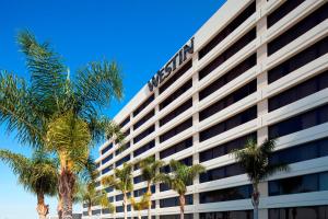 ein hohes weißes Gebäude mit Palmen davor in der Unterkunft The Westin Los Angeles Airport in Los Angeles