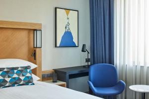 een slaapkamer met een bed en een blauwe stoel en een bureau bij Courtyard by Marriott Exeter Sandy Park in Exeter