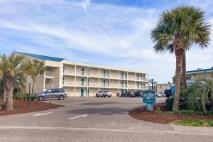 un gran edificio con palmeras y aparcamiento en The Oceanfront Litchfield Inn 251, en Pawleys Island