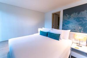 een slaapkamer met een groot wit bed met blauwe muren bij Centara Life Maris Resort Jomtien in Jomtien Beach