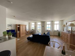 sala de estar con sofá negro y cocina en Villa Seeblick Warnemünde - Fewo mit Meerblick und Balkon direkt am Strand für 2-4 Pers, en Rostock