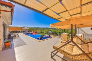 eine Außenterrasse mit einem Sonnenschirm und einem Pool in der Unterkunft Villa Isında konağı in Kaş