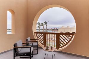 a room with a balcony with chairs and a circular window at Steigenberger Golf Resort El Gouna in Hurghada