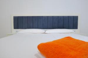 Una gran cama blanca con una manta naranja. en Davide Rooms, en Sarandë