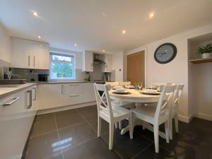 une cuisine avec une table, des chaises et une horloge murale dans l'établissement Modern 4-bed Cottage Llanwrst Town Centre & Parking - Snowdonia! near Betws-y-Coed, à Llanrwst