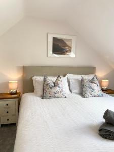 - une chambre avec un lit blanc et des oreillers dans l'établissement Modern 4-bed Cottage Llanwrst Town Centre & Parking - Snowdonia! near Betws-y-Coed, à Llanrwst