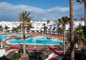 uma vista aérea de uma piscina de resort com palmeiras em Apartamentos Hesperia Bristol Playa em Corralejo