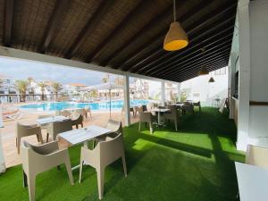 um restaurante com mesas e cadeiras e uma piscina em Apartamentos Hesperia Bristol Playa em Corralejo