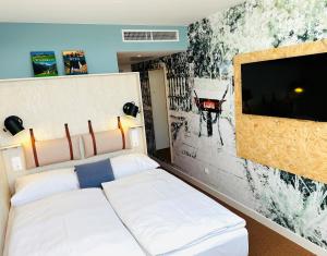 een slaapkamer met een bed en een muur met een tv bij greet Wien City Nord in Wenen