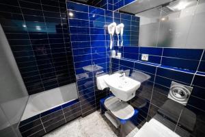 a blue tiled bathroom with a sink and a toilet at Hostal Albany in León