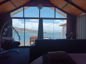 - un salon avec une grande fenêtre donnant sur l'océan dans l'établissement Uros Lake Titicaca Lodge, à Puno