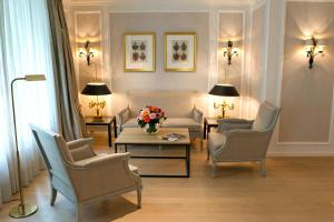 uma sala de estar com cadeiras e uma mesa com um vaso de flores em Hotel München Palace em Munique