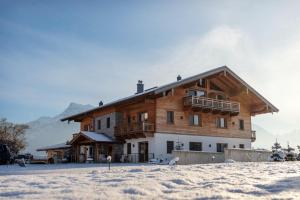 ein großes Holzgebäude im Schnee davor in der Unterkunft Madlhof in Himmelreich