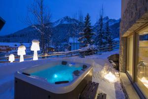 a hot tub on a patio in the snow at Residence Aspen in Arabba