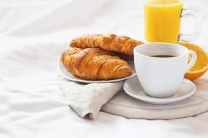 un plateau de croissants et une tasse de jus d'orange dans l'établissement Villa Thermae Nancy, à Nancy