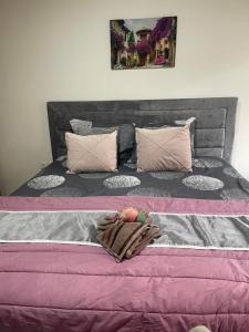 uma cama grande com lençóis e almofadas cor-de-rosa e cinza em ALOHA apartment em Novi Pazar