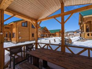 une terrasse couverte en bois avec une table en bois dans la neige dans l'établissement LOG HOUSE, à Bakuriani