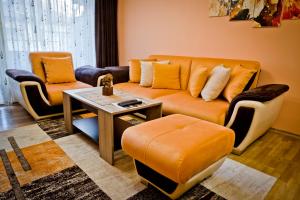 - un salon avec un canapé orange et une table dans l'établissement Sunflower Apartment City Center, à Plovdiv