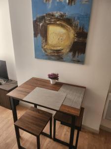 uma mesa e um banco num quarto com uma pintura em Pied à terre tout confort em Bar-le-Duc