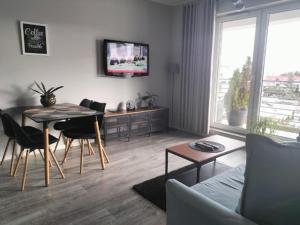 ein Wohnzimmer mit einem Tisch und Stühlen sowie einem TV in der Unterkunft Apartament przy Aquaparku w Redzie in Rumia