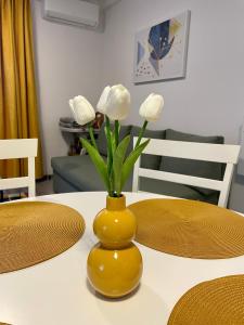 eine gelbe Vase mit weißen Blumen auf dem Tisch in der Unterkunft Apartament Mara in Baile Felix