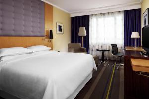 een hotelkamer met een groot wit bed en een bureau bij Sheraton Brussels Airport Hotel in Zaventem