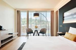 a bedroom with a bed and a table with chairs at Lyon Marriott Hotel Cité Internationale in Lyon