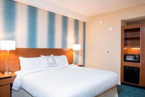 Fairfield Inn & Suites by Marriott Indianapolis Carmel في كارميل: غرفة نوم بسرير ابيض كبير وتلفزيون